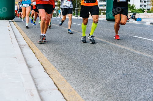 Preview: Legs of unrecognizable runners running towards the finish line of an amateur race.