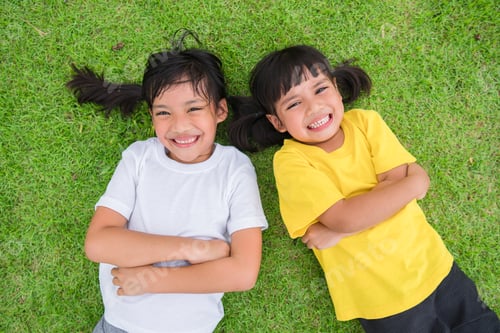 Preview: Closeup of happy asian children lying on the green grass