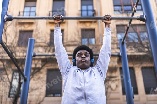 Preview: Confident african american young man doing pull-ups in calithenics park