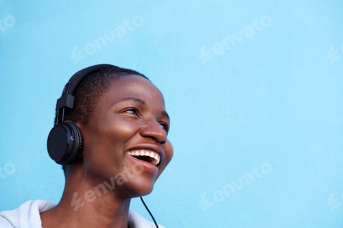 Preview: smiling african woman listening to music with headphones