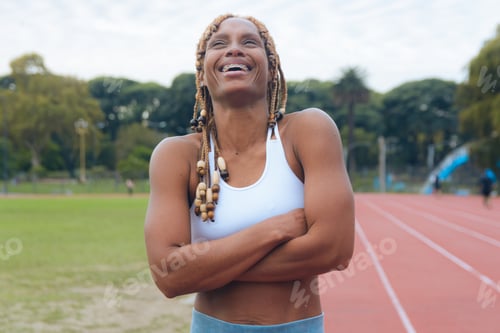 Preview: Portrait of a young African sportswoman on the court, arms crossed, laughing enthusiastically