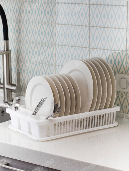 Preview: A plastic dish drying rack stands at the sink in the kitchen with clean dishes inside.