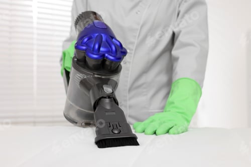 Preview: Woman in gloves disinfecting mattress with vacuum cleaner indoors, closeup
