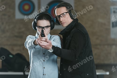 Preview: female customer aiming gun at camera in shooting gallery