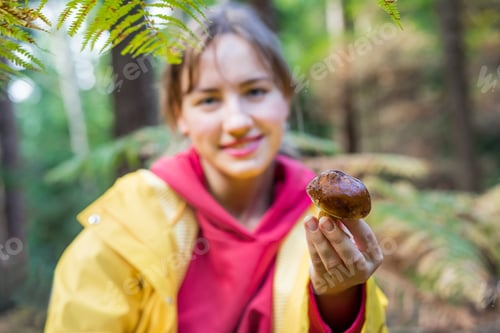 Preview: Close up just picked mushroom in a hand of young smiling woman holding in the autumn forest.