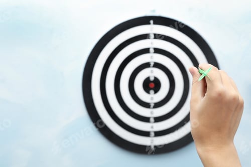 Preview: Woman throwing green arrow at dart board on light blue background, closeup. Space for text