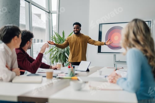 Preview: Marketing manager presenting business strategy to creative team in meeting room