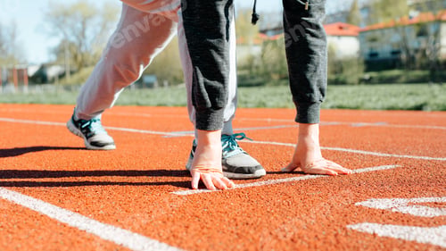 Preview: Outdoor workout. Close-up of woman practicing running on stadium treadmill, standing at low start