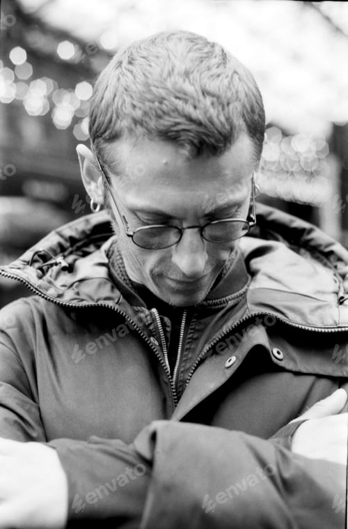 Preview: Pensive man wearing glasses and winter jacket in monochrome analog style