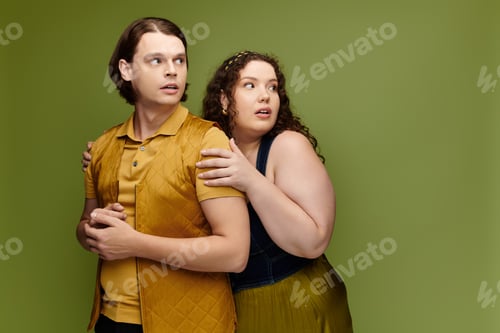 Preview: Young plus size woman and her male friend pose together in a vibrant green setting during the day
