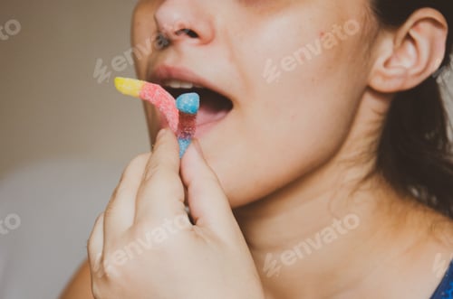 Preview: woman holding jelly candies and putting it on the mouth