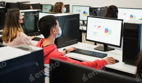 Preview: Young students using computers inside business class wearing safety masks