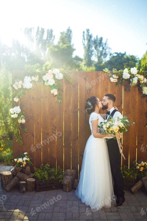 Preview: Stylish couple of happy newlyweds posing in the sun Pretty bride and stylish groom. Romantic moment.