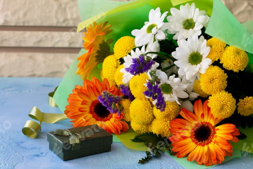 Aperçu: Basket bouquet of gerbera and chrysanthemums on a stone background.