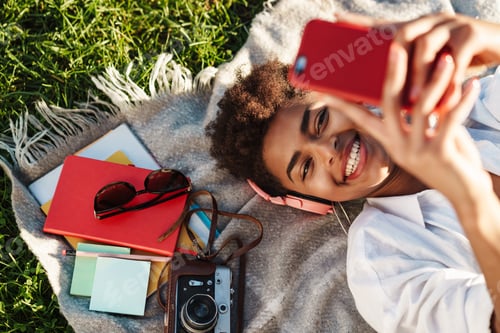 Preview: Woman lying outdoors while using mobile phone