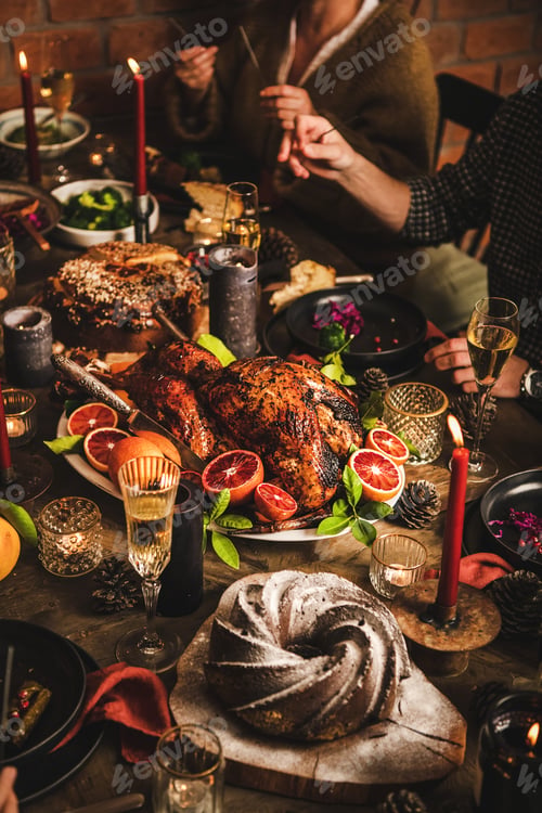 Preview: Family celebrating Christmas over festive table with chicken, cake, champagne