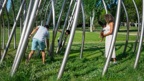 Preview: Latin family of father mother son and baby playing in a park on a summer day