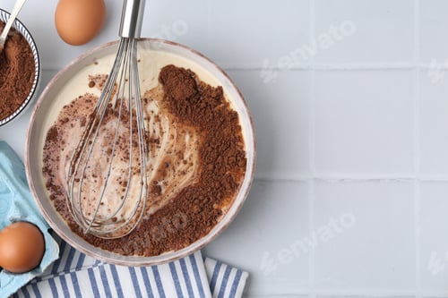 Preview: Adding cocoa powder into bowl with dough at white tiled table, flat lay. Space for text