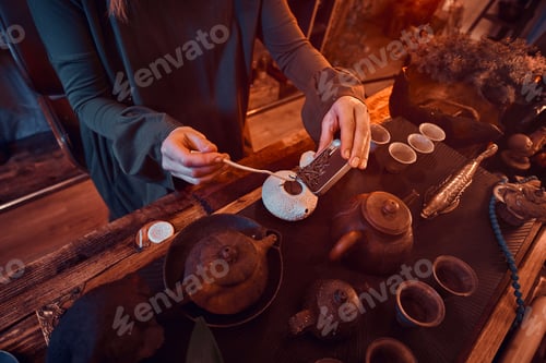 Preview: Oriental master wearing a dress in the dark room with a wooden interior. Chinese tea ceremony
