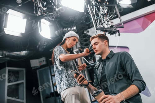 Preview: Young man is preparing for TV online broadcast. Woman helps with make up