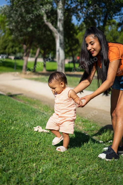 Preview: One-year-old Latin baby girl learning to walk outdoors with the help of her mother