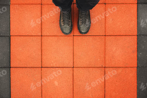 Preview: Man standing on the square shaped concrete pavement slabs,top view of dirty boots on sidewalk