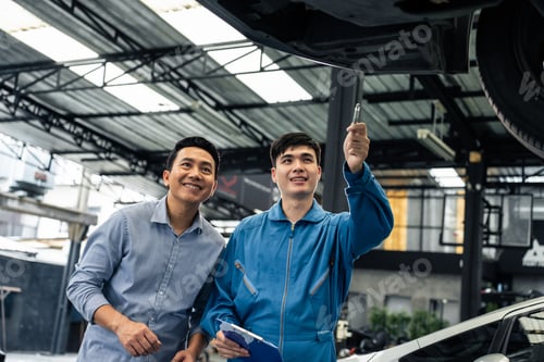 Preview: Asian automotive mechanic explain car condition to client in garage.