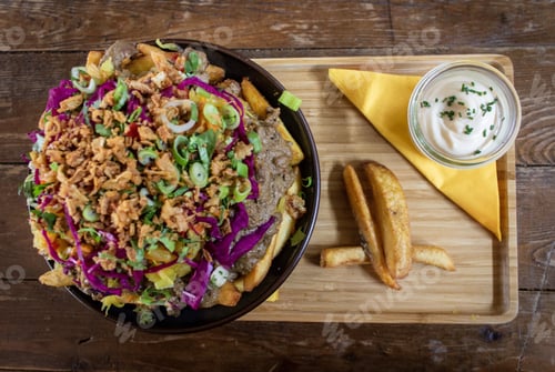 Preview: Overhead shot of a dish with potatoes, meat and sliced vegetables in a bowl near a sauce