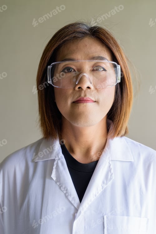 Preview: Confident transgender non-binary person in lab coat and protective glasses