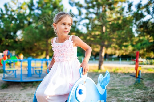 Preview: A lovely beautiful girl in a wonderful pink delicate dress sits on a small swing in a warm sunny