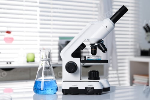 Preview: Laboratory analysis. Flask with blue liquid and microscope on white table indoors