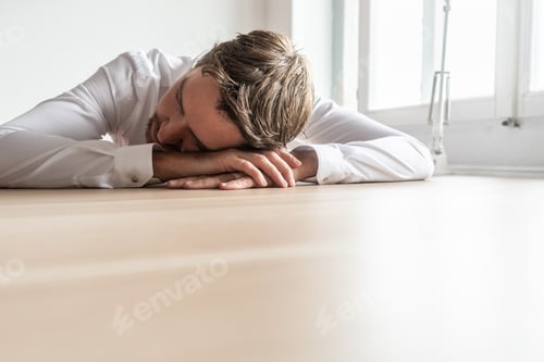 Preview: Tired businessman resting at his office desk