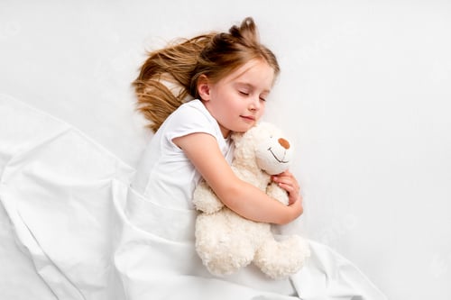 Preview: Girl hugging teddy bear laying on bed
