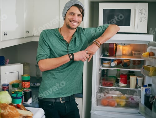 Preview: Fancy a snack. Portrait of a smiling young man standing by an open fridge in his kitchen.