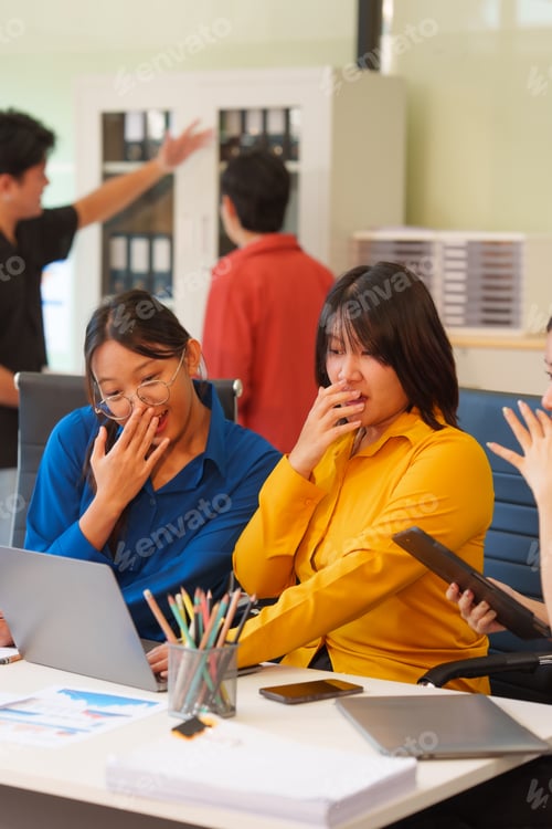 Preview: A young Asian startup business team collaborating on a project in a modern office, using a laptop