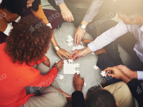 Preview: Piece by piece. High angle shot of a group of coworkers putting a puzzle together.