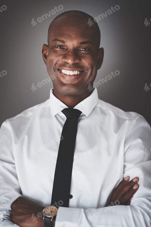 Preview: Smiling young African businessman standing against a gray background