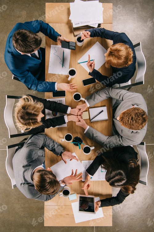 Preview: Top view of business partners working at table with coffee, documents and gadgets in office