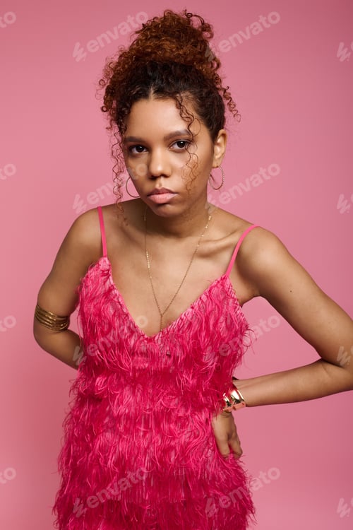 Preview: Stylish young woman poses confidently in vibrant pink attire against a soft pink background