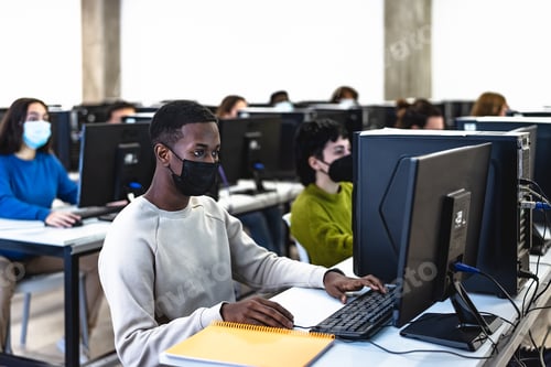 Preview: Young multiracial students taking an exam in high school while wearing face mask