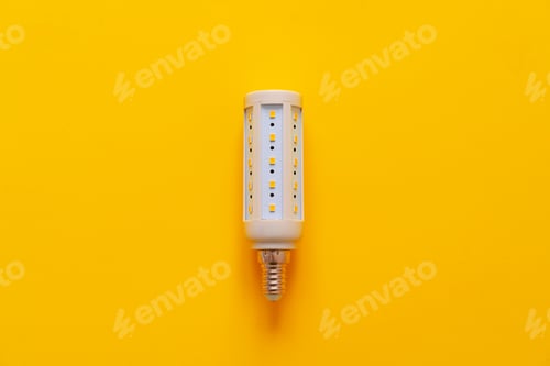 Preview: Light bulb on yellow paper background top view