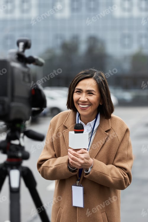 Preview: Dynamic multiracial journalist in a beige coat confidently reports news outdoors