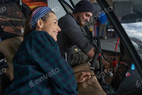 Preview: Bearded man and laughing woman working together in airplane cockpit in hangar