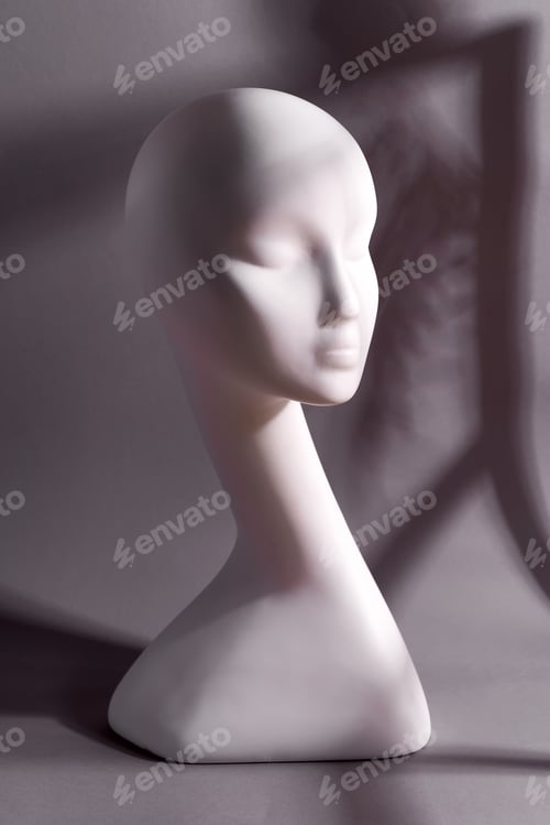 Vorschau: Kopf einer weißen Schaufensterpuppe auf grauem Grund. Gesichtsloses Mädchen