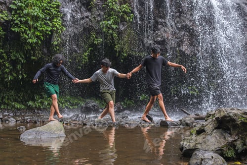 Preview: Three Adventurous Friends Exploring Nature Together Near Stunning Tropical Waterfall