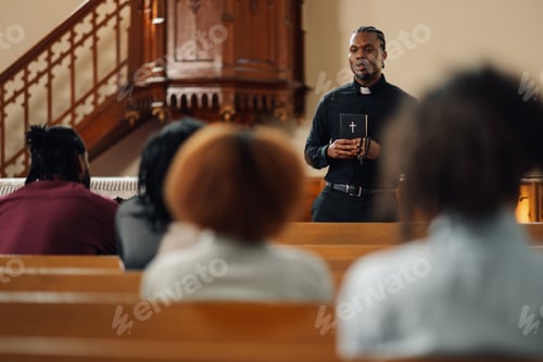 Preview: Young priest leading congregation in prayer holding bible