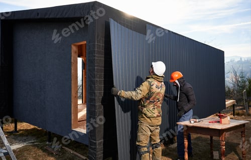 Preview: Builder installing corrugated iron sheet used as facade of future wooden frame house.