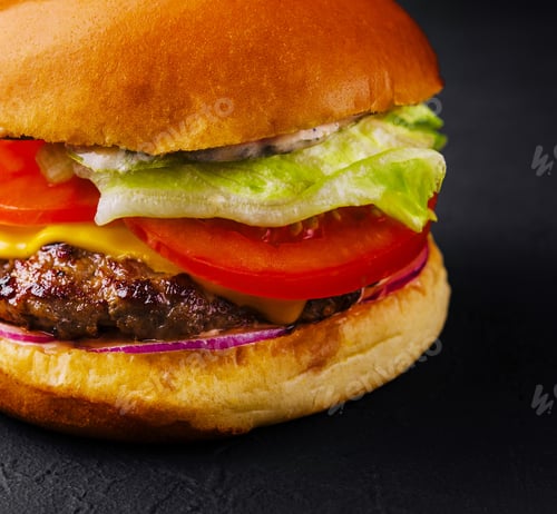 Preview: Appetizing cheeseburger on black stone closeup