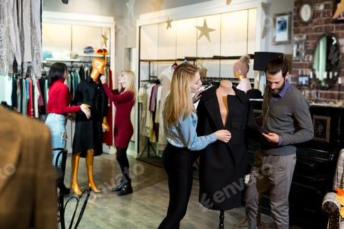 Preview: Young woman and man shopping warm jackets at the apparel store.