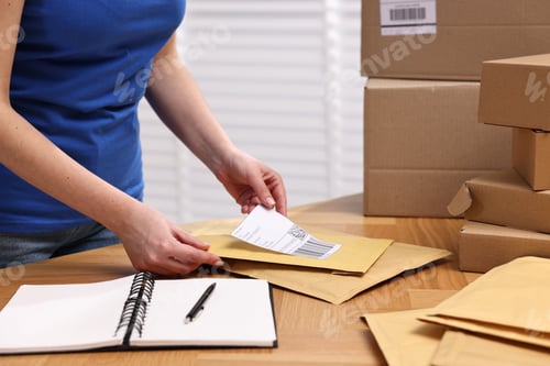 Preview: Parcel packing. Post office worker sticking barcode on bag at wooden table indoors, closeup